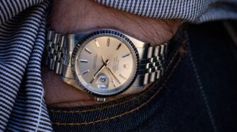 person wearing silver link bracelet round analog watch