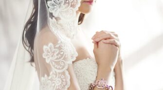 Beautiful bride in lace gown and veil, captured in soft lighting.