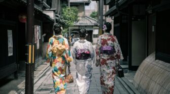 Three women in colorful kimonos walking through a traditional street in Kyoto, Japan.