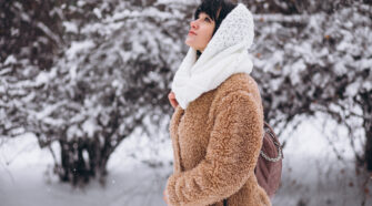 Young happy woman in warm cloths in a winter park